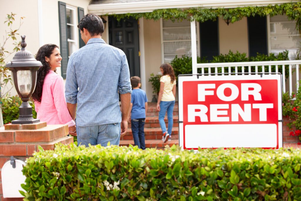 Family viewing house with "For Rent" sign.
