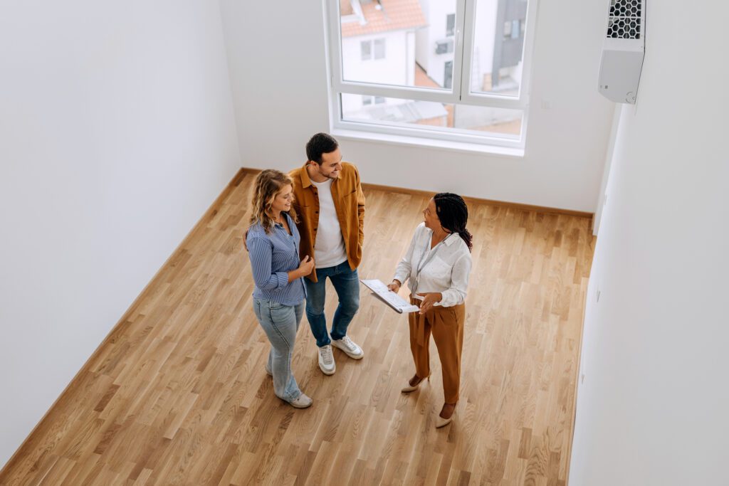 Couple viewing empty room with realtor.