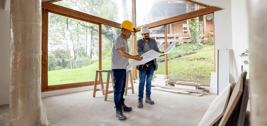 Construction workers reviewing building plans indoors.
